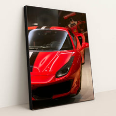 This photo shows the front left side of a red Ferrari with a black and white racing stripe, parked indoors, in a white frame.