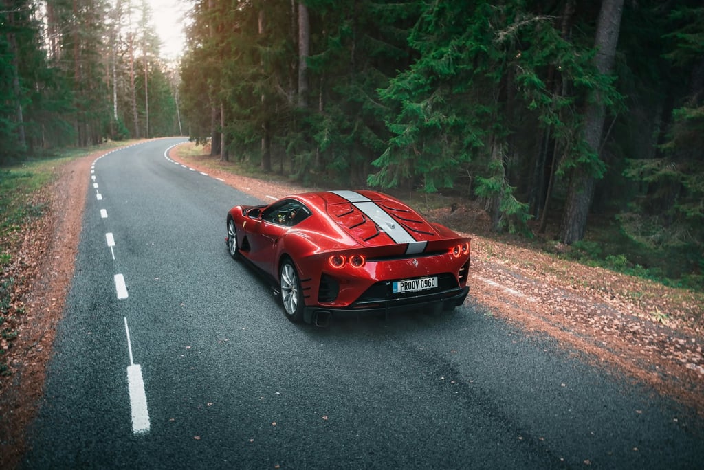 Ferrari 812 Superfast in the Forest driving along a winding road surrounded by trees, showcasing its striking design.