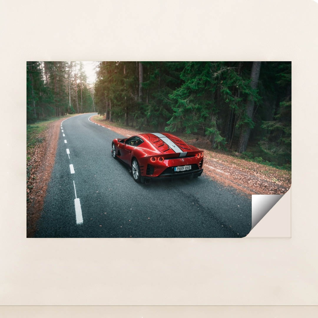 This photo shows a red Ferrari sports car with white stripes parked on a winding forest road, minimalist unframed style.