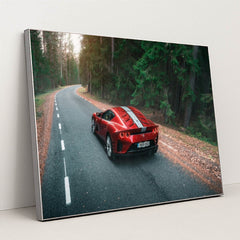 This photo shows a red Ferrari sports car with white stripes parked on a winding forest road, in a silver frame.
