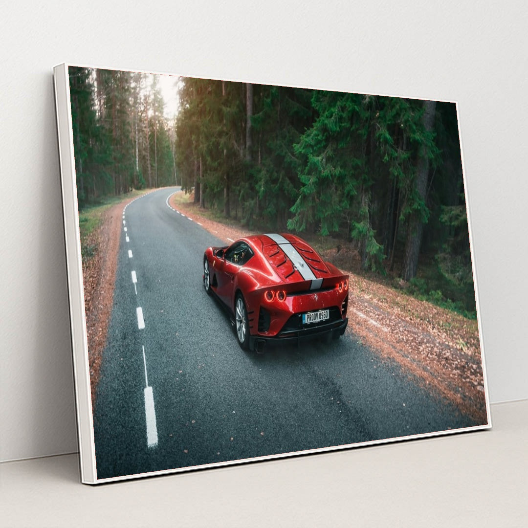 This photo shows a red Ferrari sports car with white stripes parked on a winding forest road, in a white frame.