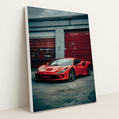 This photo shows a red Ferrari F8 Tributo parked in front of weathered red garage doors on a cloudy day, in a white frame.