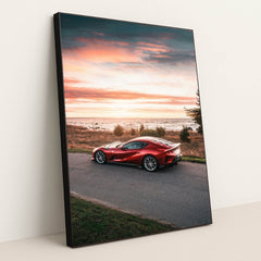 This photo shows a red Ferrari 812 Superfast parked by the seaside at sunset, in a black frame.