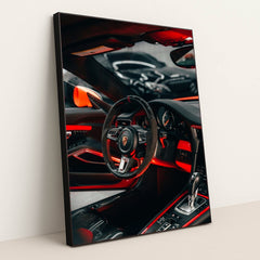 This photo shows the interior of a Porsche with a black and red steering wheel, paddle shifters, and orange accents, in a black frame.