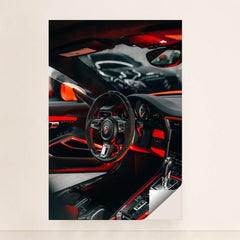 This photo shows the interior of a Porsche with a black and red steering wheel, paddle shifters, and orange accents, minimalist unframed style.
