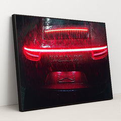This photo shows the rear of a Porsche 911 Carrera 4 GTS during heavy rain at night with bright red taillights, in a black frame.
