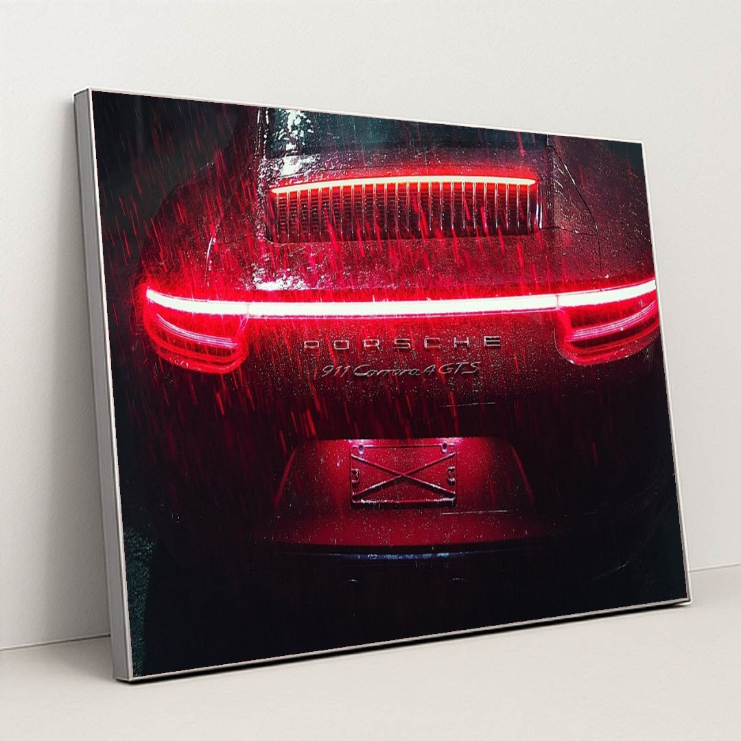 This photo shows the rear of a Porsche 911 Carrera 4 GTS during heavy rain at night with bright red taillights, in a silver frame.