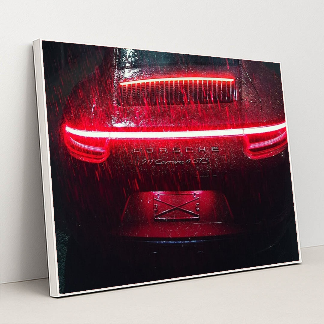 This photo shows the rear of a Porsche 911 Carrera 4 GTS during heavy rain at night with bright red taillights, in a white frame.