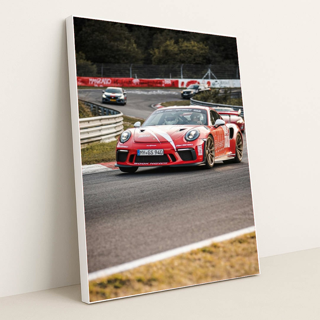 This photo shows a red Porsche GT3 RS race car with white stripes driving on a track during a motorsport event, in a white frame.