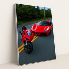 This photo shows a red Ducati motorcycle and a red Ferrari sports car parked side by side on a rural road, in a silver frame.