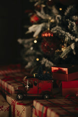 Lisett Kruusim - A cozy Christmas setup featuring a red toy car, gifts, and a decorated tree.