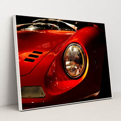 This photo shows a close-up of the front left headlight and fender of a classic red Ferrari Dino, in a white frame.