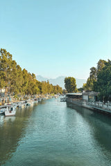 Hasan Hüseyin Korkmaz - Tranquil river scene in Hatay, Türkiye with anchored boats and lush greenery under a clear blue sky.