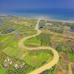 Tom Fisk - A breathtaking aerial view of lush farmland, meandering river, and coastal areas under a clear blue sky.
