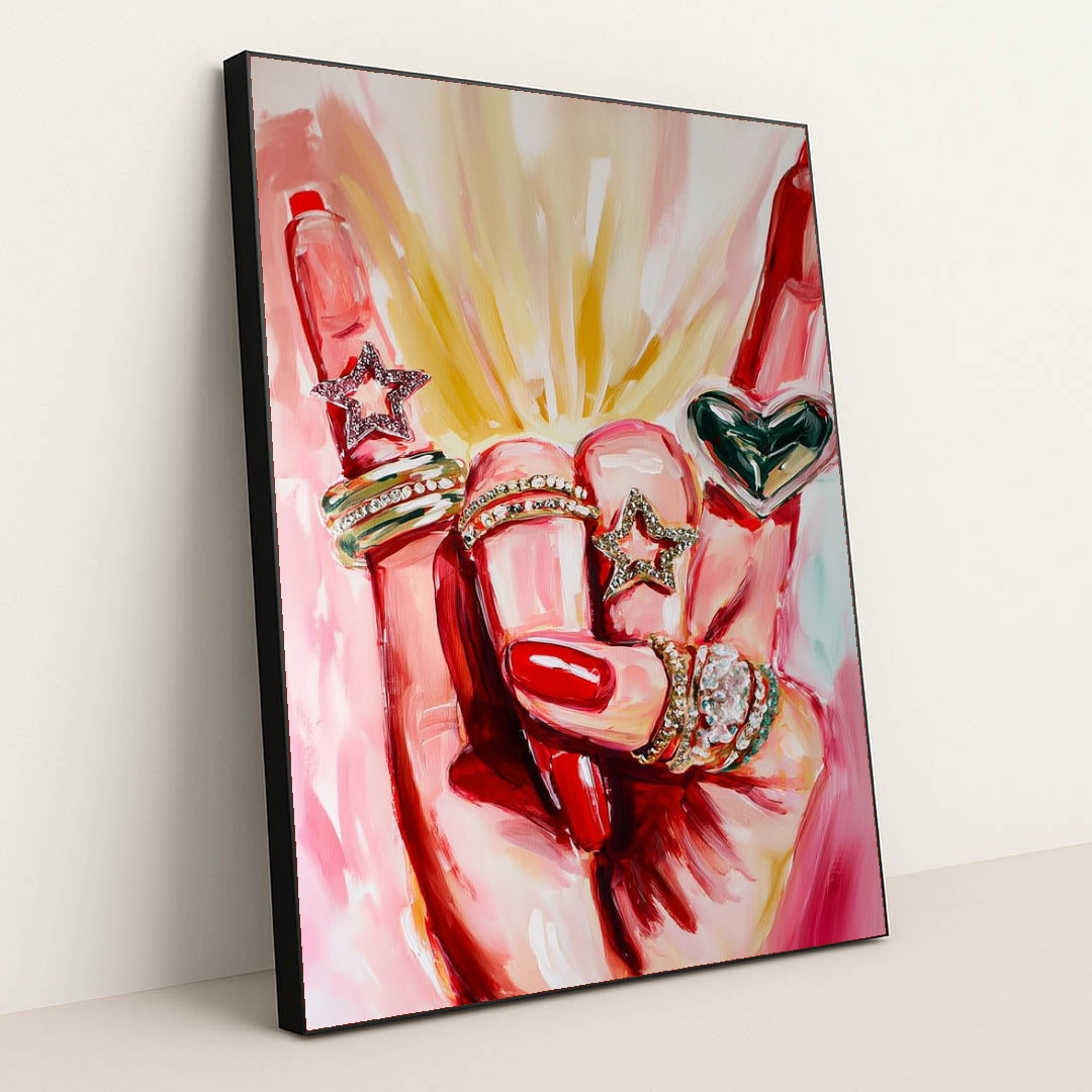 This artwork shows a hand with red nails wearing sparkly rings shaped like stars and a heart, set against pink painted brushstrokes, in a black frame.