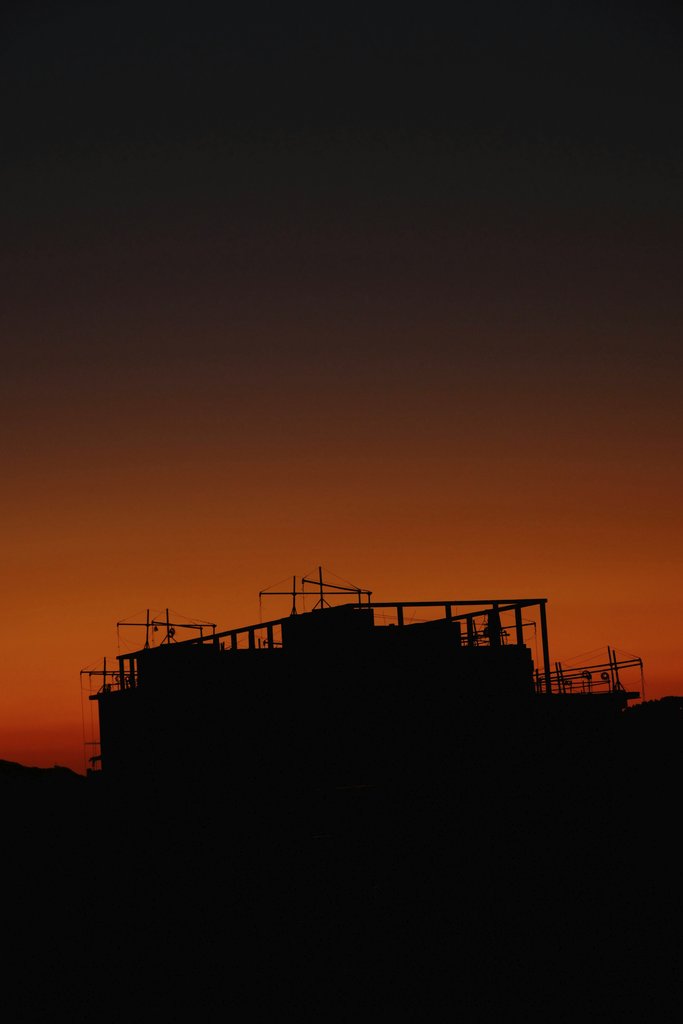billow926 - Silhouette of a building under construction with a striking red sunset sky.