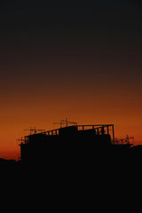 billow926 - Silhouette of a building under construction with a striking red sunset sky.