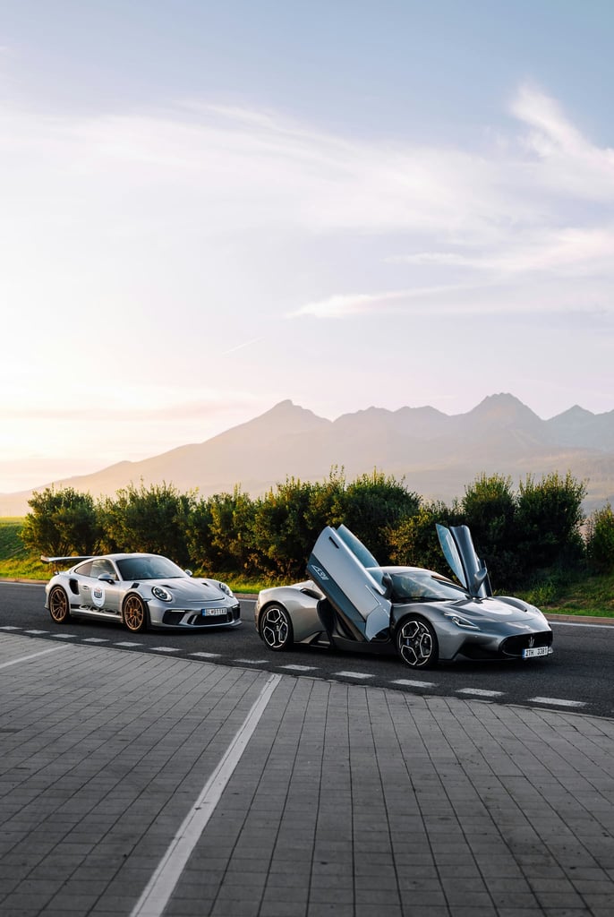 Maserati MC20 Meets Porsche GT3 - Stunning car wall art featuring two supercars against a scenic mountain backdrop.