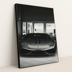 This photo shows the front view of a matte grey Lamborghini Huracán parked indoors, in a black frame.