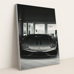 This photo shows the front view of a matte grey Lamborghini Huracán parked indoors, in a silver frame.