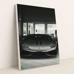 This photo shows the front view of a matte grey Lamborghini Huracán parked indoors, in a white frame.