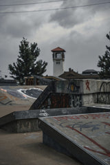 Connor McManus - Discover a graffiti-covered skatepark under an overcast sky, with a classic clock tower backdrop.