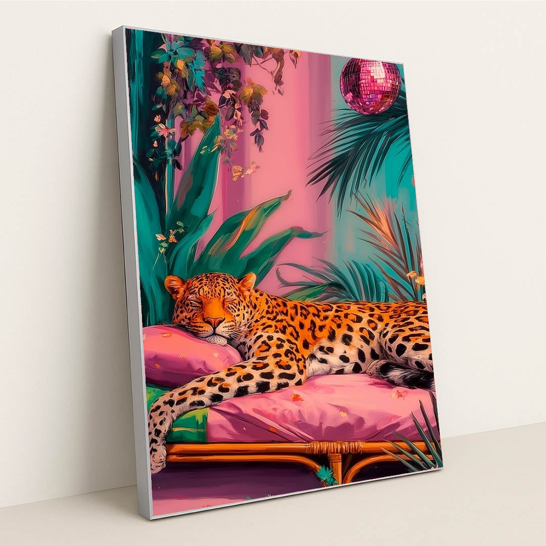 This artwork shows a lounging leopard on a pink couch surrounded by tropical plants and a sparkling disco ball, in a silver frame.