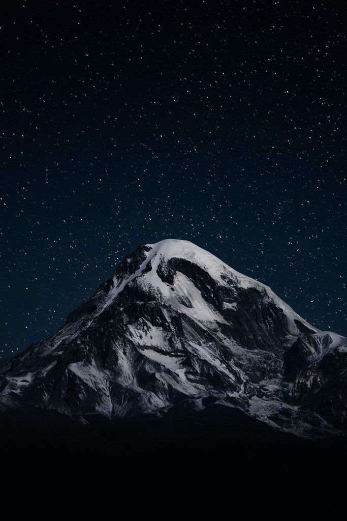 Maksim Samuilionak - A snow covered mountain under a night sky filled with stars photo