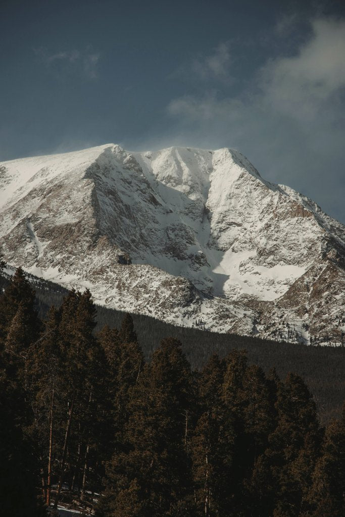 Jacob Moore - Stunning winter view of snow-covered Rocky Mountains towering over an evergreen forest.