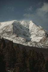 Jacob Moore - Stunning winter view of snow-covered Rocky Mountains towering over an evergreen forest.
