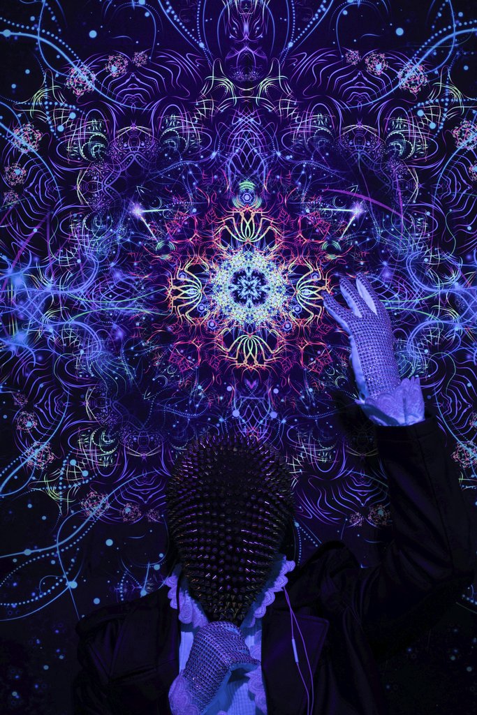 Sid Dalal - A person in a studded mask poses against a vibrant neon kaleidoscope pattern, creating a surreal visual.