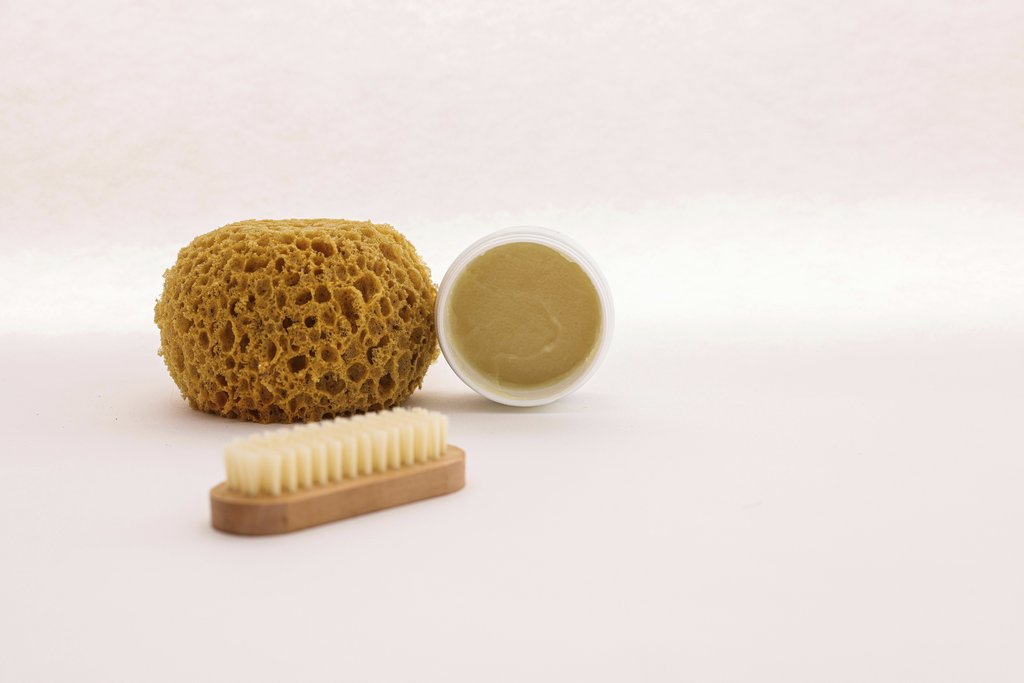 Cup of Couple - A natural sponge, brush, and skincare cream arranged for a minimalist spa setting.