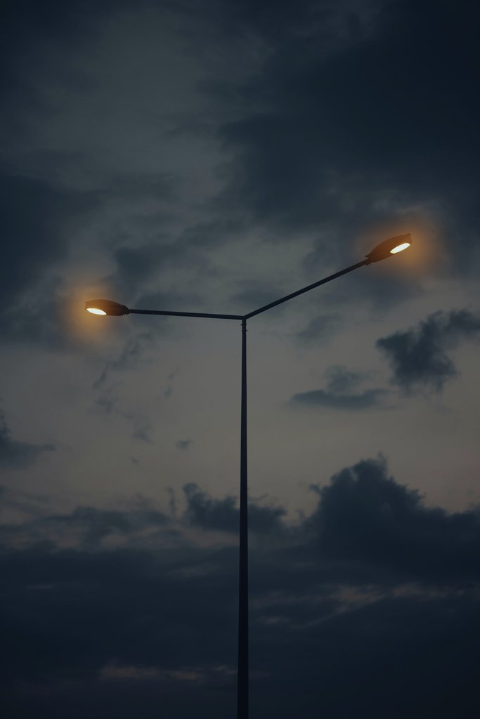 Atahan Demir - Streetlamp illuminates evening sky with dramatic clouds creating a moody atmosphere.