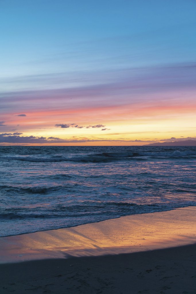 Joshua Woroniecki - Vibrant sunset over Los Angeles beach with waves and colorful sky reflections.