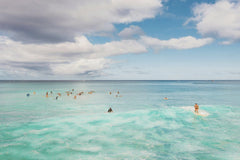 Jess Loiterton - Surfers riding waves under a vibrant sky in Hawaii, showcasing the island's adventurous spirit.
