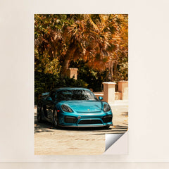 This photo shows a metallic blue Porsche sports car parked under tropical palm trees on a sunny day, unframed style.