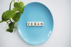 Vegan Liftz - A blue plate with the word 'VEGAN' and a leafy plant, symbolizing a plant-based diet.