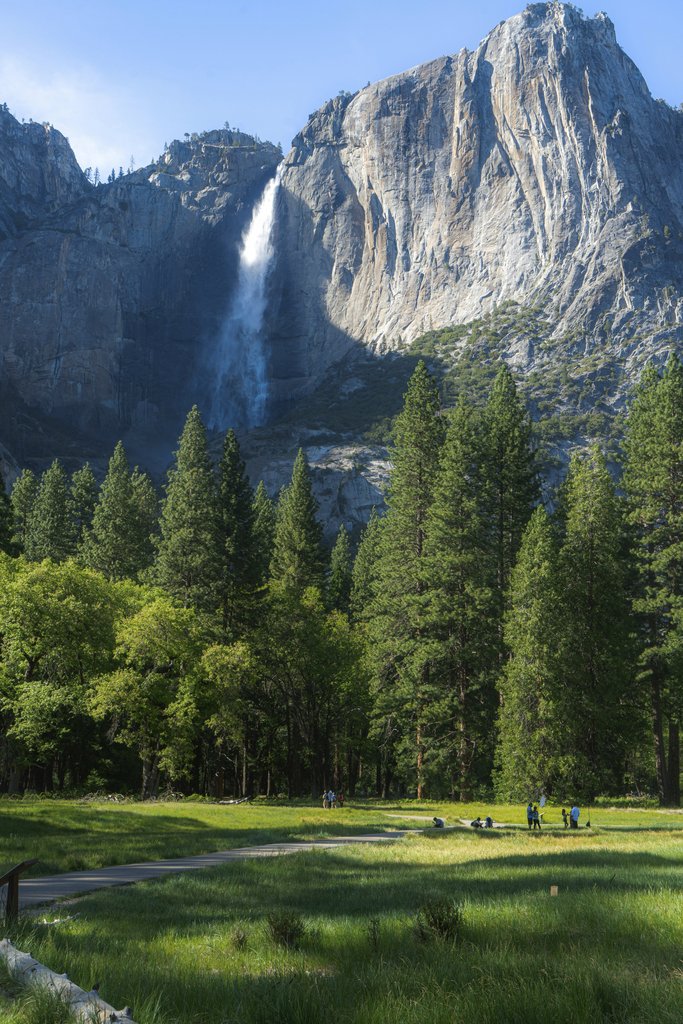 Yuanpang Wa - Breathtaking view of Yosemite's waterfall cascading down rocky cliffs with lush greenery and trees.