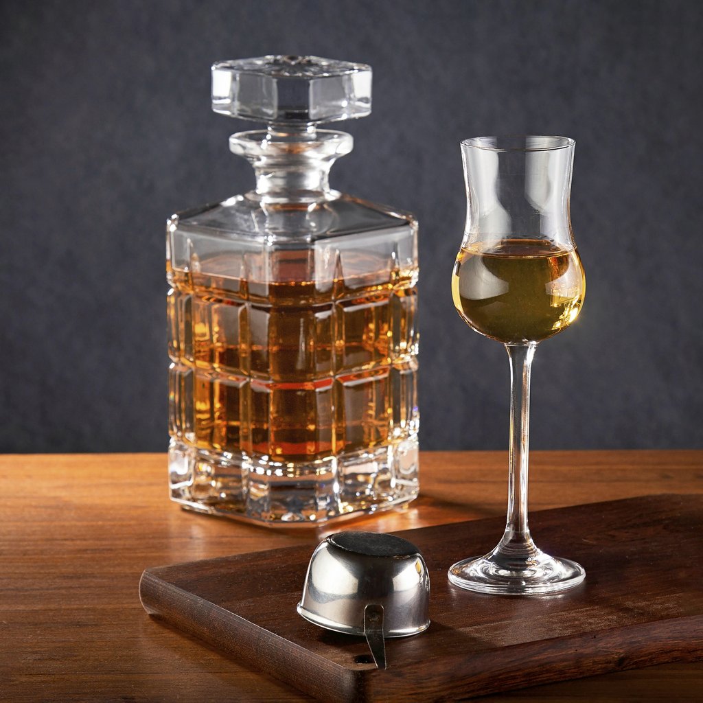 Marcelo Verfe - A sophisticated display of a crystal decanter and whiskey glass on a wooden table, exuding luxury.