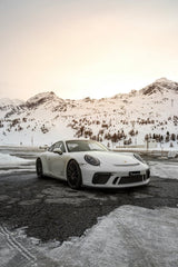 Porsche 911 GT3 in Alpine Stillness, a white car on icy pavement with snow-capped peaks and golden light.