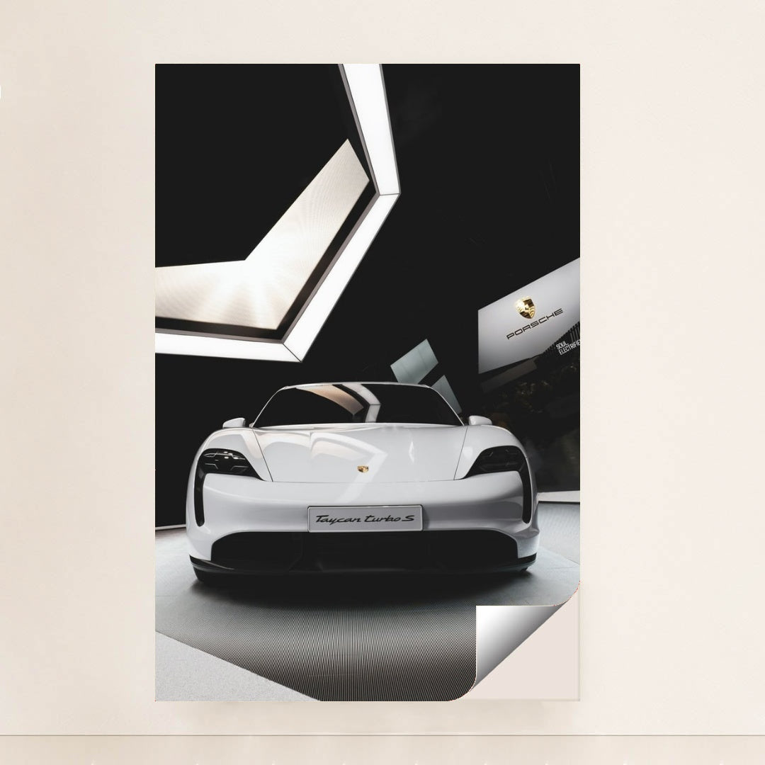 This photo shows the front view of a white Porsche Taycan Turbo S on display in a modern showroom, minimalist unframed style.