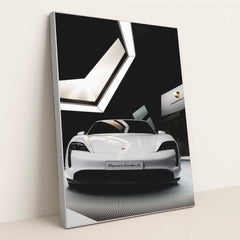 This photo shows the front view of a white Porsche Taycan Turbo S on display in a modern showroom, in a silver frame.