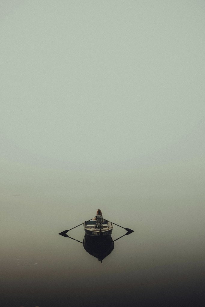 Connor McManus - A peaceful scene of a lone person rowing a boat in a misty, fog-covered lake.