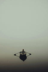 Connor McManus - A peaceful scene of a lone person rowing a boat in a misty, fog-covered lake.