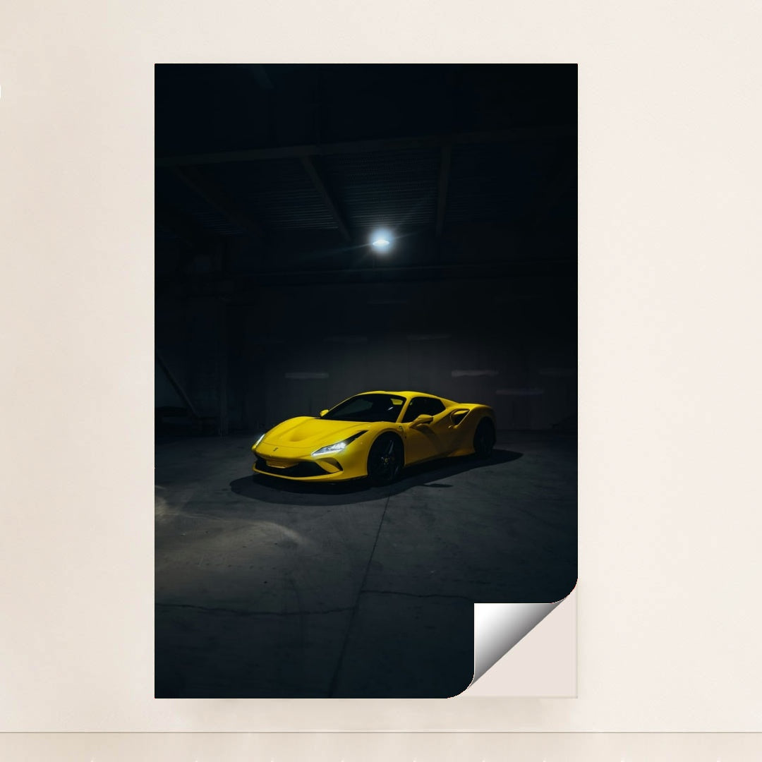 This photo shows a yellow Ferrari sports car spotlighted in a dark, empty garage, minimalist unframed style.