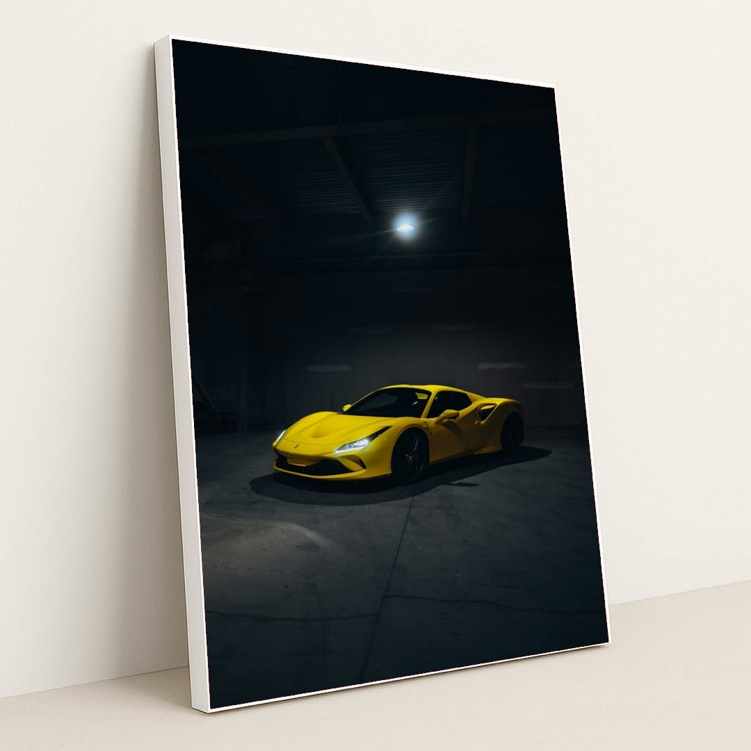 This photo shows a yellow Ferrari sports car spotlighted in a dark, empty garage, in a white frame.