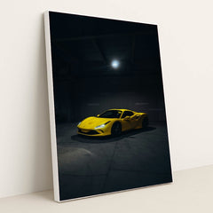 This photo shows a yellow Ferrari sports car spotlighted in a dark, empty garage, in a white frame.
