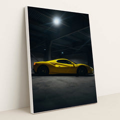 This photo shows a yellow Ferrari sports car in a dimly lit industrial garage, side view captured under overhead lights, in a white frame.