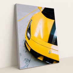 This photo shows the front end of a yellow Ferrari 488 Pista with black and silver racing stripes indoors, in a silver frame.