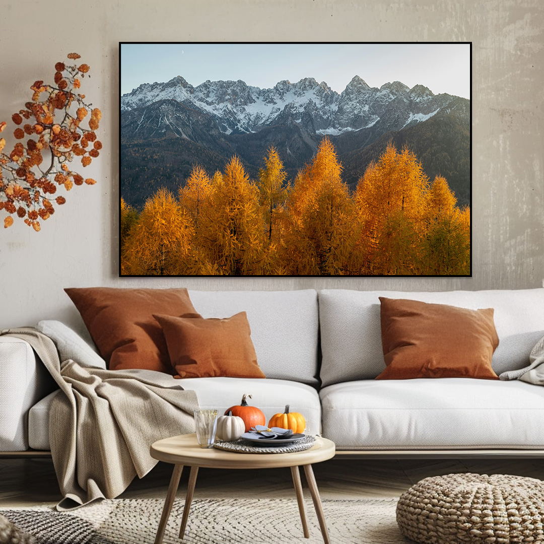 Living room with a large framed picture of autumn trees and mountains, a white sofa with brown and orange pillows, and a small round table.